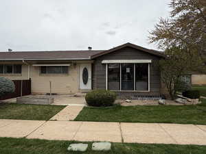 Single story home featuring a shingled roof, brick siding, and a front lawn