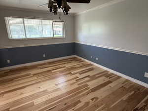 Unfurnished room with light wood-type flooring, ornamental molding, and a ceiling fan