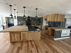 Kitchen featuring a kitchen breakfast bar, decorative light fixtures, light wood-style floors, a large island, and a textured ceiling