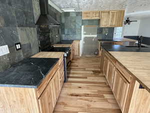 Kitchen featuring electric range, light wood-style floors, wooden counters, light wood finish cabinets, and ceiling fan