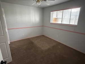 Spare room featuring dark carpet and a ceiling fan