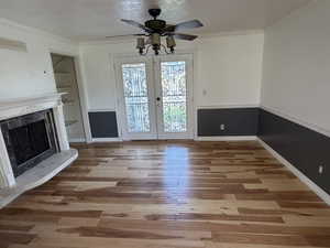 Doorway to outside featuring french doors, ceiling fan, wood finished floors, a fireplace, and crown molding