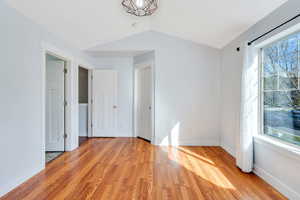 Spare room with light wood-style flooring and lofted ceiling