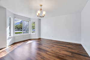 Unfurnished dining area featuring a chandelier and dark wood-style floors