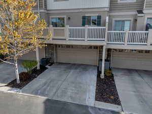 View of front of house with stone siding, an attached garage, concrete driveway, and a balcony