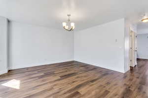 Spare room featuring a chandelier and dark wood finished floors