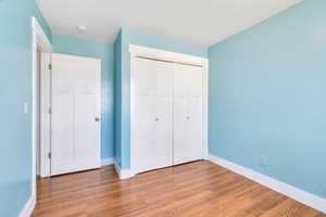 Unfurnished bedroom featuring wood finished floors and a closet