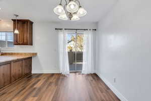 Unfurnished dining area featuring a chandelier and dark wood finished floors
