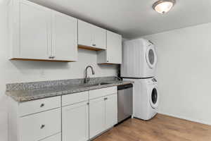Laundry area featuring light wood finished floors and stacked washer / drying machine
