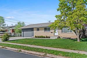 Single story home with a front lawn, an attached garage, brick siding, and concrete driveway
