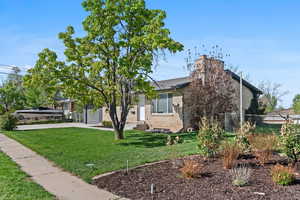 View of front facade with brick siding, a chimney, concrete driveway, and a garage