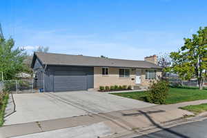 Single story home featuring a gate, a chimney, an attached garage, brick siding, and driveway