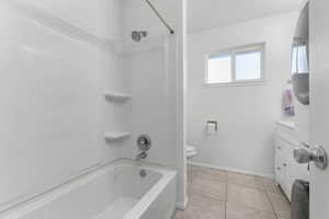 Full bathroom with vanity, shower / washtub combination, light tile patterned floors, and washer / dryer