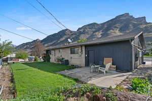 Rear view of house featuring a mountain view, a lawn, a patio area, and brick siding