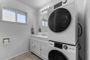 Laundry area featuring stacked washing machine and dryer and light tile patterned floors