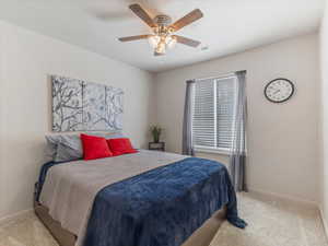 Bedroom with light colored carpet and a ceiling fan