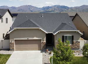 View of front of property with stone siding, a gate, a mountain view, an attached garage, and stucco siding