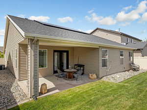 Back of house with a covered patio, roof with shingles and solar panels