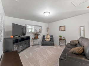Living room with carpet flooring and a textured ceiling
