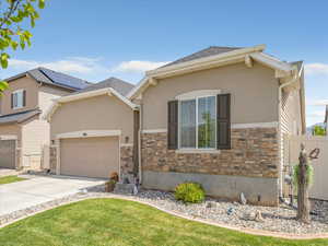 View of front of home featuring concrete driveway, a garage, stone siding, stucco siding, and roof with shingles