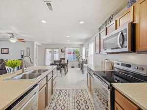 Kitchen featuring stainless steel appliances, light countertops, ceiling fan, light tile patterned flooring, and recessed lighting