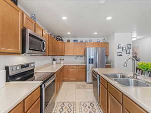 Kitchen featuring stainless steel appliances, light countertops, recessed lighting, wood finish cabinets, and light tile patterned floors