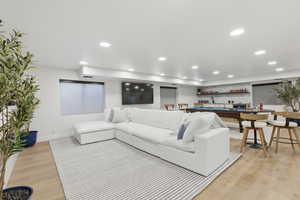 Living area featuring light wood finished floors, billiards, recessed lighting, and bar