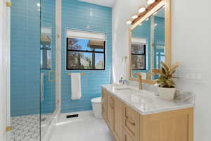 Bathroom with vanity, plenty of natural light, tile walls, light tile patterned flooring, and a stall shower