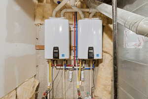 Utility room featuring tankless water heater and heating unit