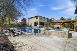 View of swimming pool with a gazebo, patio surround, a fenced backyard, and outdoor lounge area