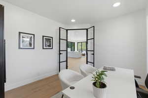 Office with light wood-style flooring and recessed lighting