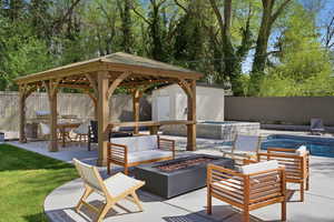 Fenced backyard with a patio area, a gazebo, a storage unit, and an outdoor living space with a fire pit