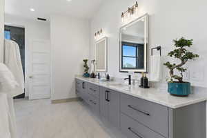 Bathroom with double vanity, plenty of natural light, light marble finish flooring, and recessed lighting