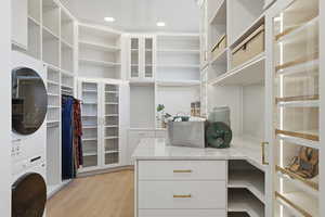 Walk in closet featuring stacked washer and dryer and light wood-style floors