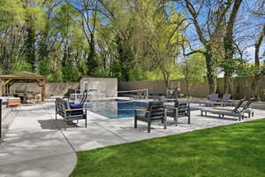 View of pool featuring patio surround, a gazebo, a fenced backyard, outdoor seating, and a storage shed