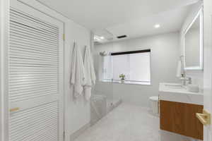 Bathroom with vanity, a closet, walk in shower, and recessed lighting
