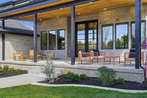 Entrance to property with stone siding, french doors, and roof with shingles