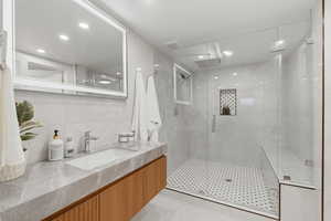 Full bathroom with vanity, a stall shower, tile walls, light tile patterned flooring, and recessed lighting