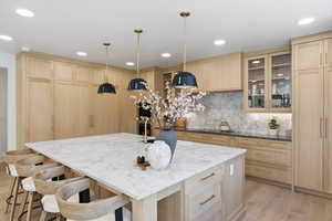 Kitchen featuring light wood finish cabinets, dark stone counters, a kitchen bar, and light wood-style floors