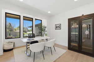Office with light wood-style floors and recessed lighting