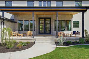 Doorway to property featuring stone siding, french doors, a porch, and stucco siding