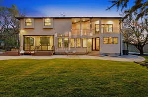 Back of property at dusk with a patio, a yard, entry steps and a balcony