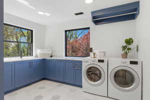 Laundry area featuring light floors, washing machine and dryer, and cabinet space