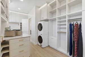 Laundry area with stacked washer and dryer, light wood finished floors, and recessed lighting