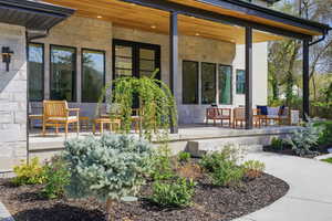 Entrance to property with stone siding, a porch, and an outdoor living space