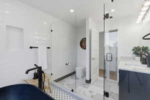 Full bathroom featuring double vanity, a shower stall, recessed lighting, and a freestanding tub