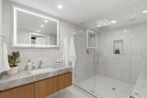 Full bathroom with vanity, a shower stall, backsplash, recessed lighting, and tile walls