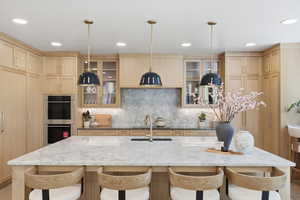 Kitchen with light wood finish cabinets, dark stone countertops, and a kitchen bar