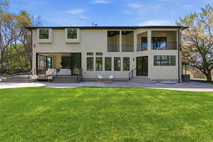 Rear view of house featuring a patio area, a yard, stucco siding, entry steps, and a balcony
