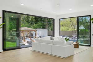 Living area featuring light wood-type flooring, recessed lighting, and view of scattered trees